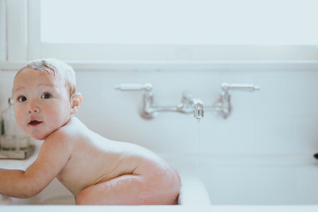 nakedbabylyingonwhiteceramicbathtub